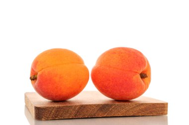 Beyaz arka planda izole edilmiş ahşap bir tepside iki sulu kayısı..