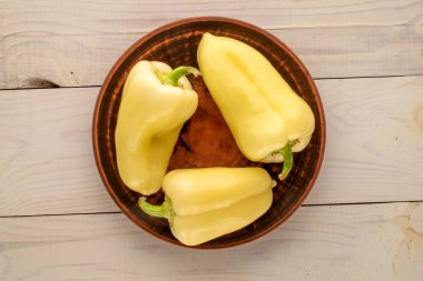 Ahşap bir masa, makro, üst görünüm üzerinde kilden bir plaka ile bir kaç olgun tatlı biber.