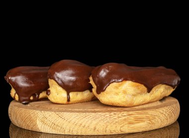 Tahta tepside kremalı üç eklem, makro, siyah arka planda izole edilmiş..