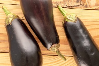 Tahta bir masada üç olgun patlıcan, makro, üst manzara..