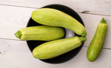 Tahta bir masada seramik tabakla dört olgun kabak, makro, üst manzara..