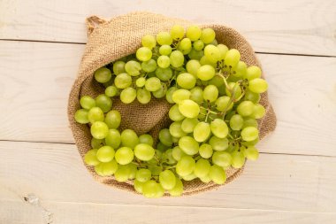 Tahta bir masa, makro, üst görünüm üzerinde jüt bir torba içinde olgunlaşmış çekirdeksiz üzümler..