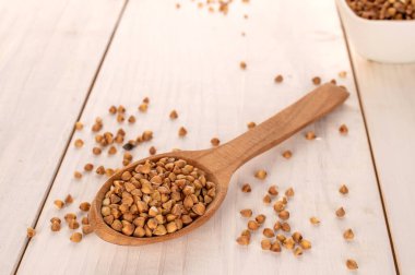 Çiğ karabuğday ahşap bir masada tahta kaşıkla inliyor, makro..