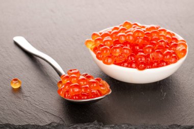 Kırmızı havyar seramik tabakta, tahtada bir kaşık, makro..
