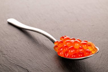 Kırmızı havyar ve bir kaşık tahtada, makro.