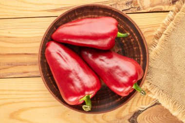 Ahşap bir masada seramik tabakta birkaç tatlı kırmızı biber, makro, üst manzara..