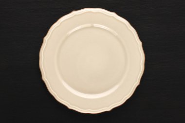 Siyah arka planda beyaz bir seramik tabak, makro, üst görünüm.