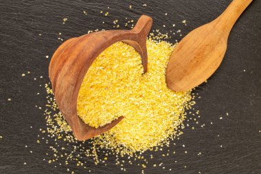 Tahta bardak ve kaşıkla pişirilmemiş mısır ezmesi, kayrak taşı, makro, üst manzara.