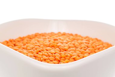 Beyaz bir tabakta pişmemiş kırmızı mercimek, makro, beyaz arka planda izole edilmiş..