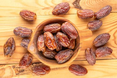 Tahta bir masada, makroda, ahşap bir kasede birkaç tatlı kurumuş çukur hurma..