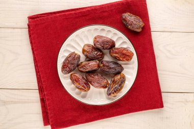 Tahta masa, makro ve üst manzara üzerinde seramik plakalı birkaç tatlı kurumuş çukur hurma..