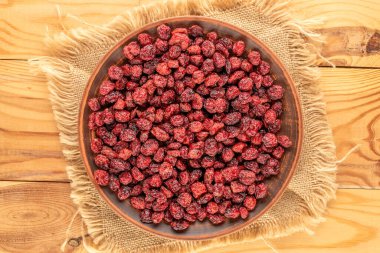 Ahşap bir masada seramik tabakla kurumuş yaban mersini, makro..