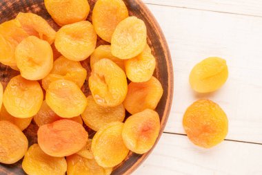 Ahşap bir masada ev yapımı tabakları olan kurutulmuş kayısılar, yakın çekim, üst manzara..