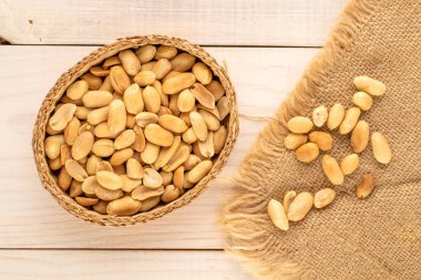 Soyulmuş, kavrulmuş fıstıklar, saman tabağında, ahşap bir masada, yakın plan, üst manzara..