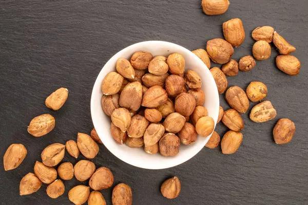 Beyaz seramik tabakta fındıklar kayrak taşı üzerinde, yakın plan, üst görünüm.