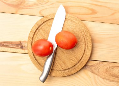Tahta bir tepside taze sulu domatesler, ahşap bir masada bıçak, yakın plan, üst görüş..