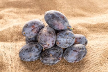 Jüt kumaşında ev aletleri olan olgun erikler, yakın plan..