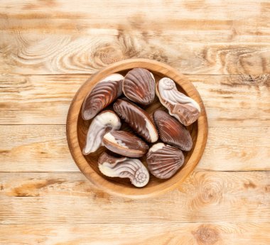 Ahşap bir masanın üzerinde seramik ve ahşap çatal bıçaklı kaç tane çikolata şekeri var?.