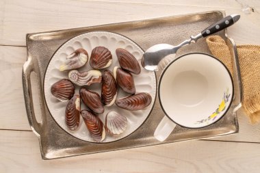 Ahşap bir masanın üzerinde seramik ve ahşap çatal bıçaklı kaç tane çikolata şekeri var?.