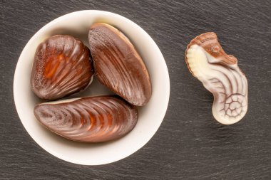 Birkaç çikolata şekeri ve seramik tabaklar kayrak taşı üzerinde, yakın plan, üst görünüm.