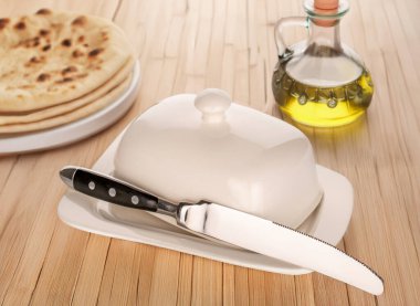 Bir adet seramik tereyağı kabı, metal bir bıçakla, yakın plan, bir bambu masasının üzerinde..