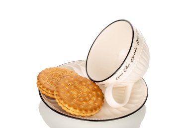 Fincan tabağında seramik bardaklı iki kurabiye, makro, beyaz arka planda izole edilmiş..