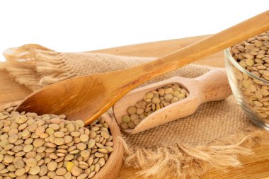 Cam bir tabakta çiğ mercimek ve ahşap bir kaşıkla ahşap bir tabak, beyaz arka planda izole edilmiş, makro..