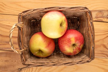 Tahta bir masada sepetteki üç organik elma, yakın plan, üst manzara..