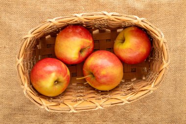 Dört organik elma bir sepetin içinde jüt kumaş üzerinde, yakın plan, üst manzara..