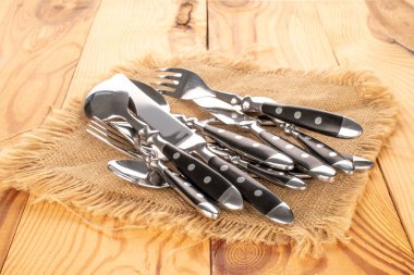 Ahşap masanın üzerinde jüt peçeteli çatal bıçak takımı, yakın plan..