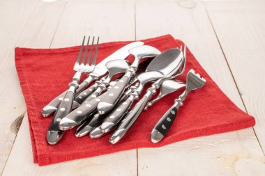 Ahşap bir masanın üzerinde keten peçeteli çatal bıçak takımı, yakın plan..