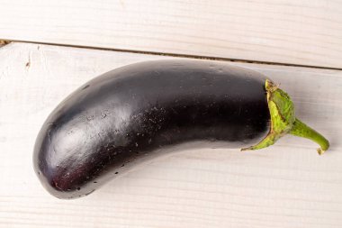 Bir koyu mor organik patlıcan, yakın plan, beyaz ahşap bir masa üzerinde, üst manzara..