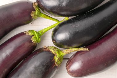 Birkaç koyu mor organik patlıcan, yakın plan, beyaz ahşap bir masa, üst manzara..