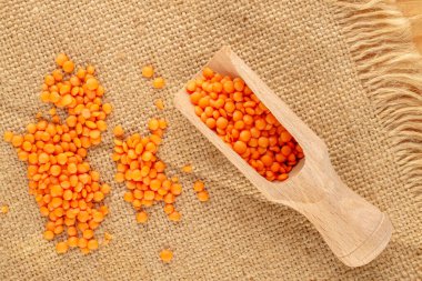 Kırmızı mercimek tahta kaşıkta jüt peçetede, yakın plan, üst manzara.