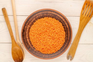 Seramik tabakta kırmızı mercimek, tahta bir kaşıkla ahşap bir masa, yakın çekim, üst manzara..