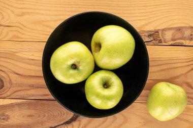 Ahşap bir masada seramik bir tabakta birkaç tane yeşil elma, yakın plan, üst manzara..