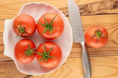 Tahta bir masada seramik tabakla sulu kırmızı domatesler, üst manzara, yakın çekim..