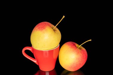 Kırmızı seramik bardaklı iki sulu elma, makro, siyah arka planda izole edilmiş..