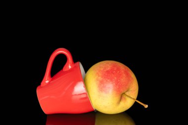 Kırmızı seramik bardaklı sulu bir elma, makro, siyah arka planda izole edilmiş..