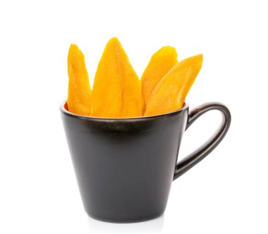 Beyaz arka planda seramik bardakla izole edilmiş kurutulmuş mango dilimleri, yakın plan..