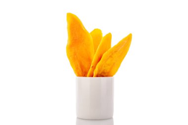 Beyaz arka planda seramik bardakla izole edilmiş kurutulmuş mango dilimleri, yakın plan..