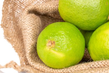 Beyaz arka planda izole edilmiş jüt çantasındaki birkaç sulu limon. Yakın plan..