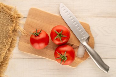 Tahta bir mutfak tahtasında kırmızı sulu domatesler, ahşap bir masa, yakın plan, üst manzara..