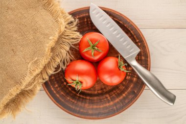 Kil tabakta kırmızı sulu domatesler Ahşap bir masada, yakın plan, üst manzara.