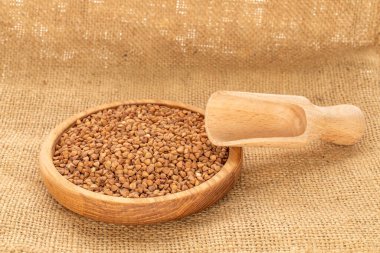 Ahşap bir tabakta çiğ karabuğday, jüt kumaş, makro.