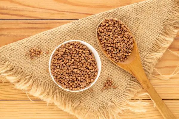 Ahşap bir masada mutfak gereçleri olan çiğ karabuğday, üst manzara, makro.