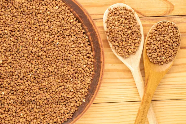 Ahşap bir masada mutfak gereçleri olan çiğ karabuğday, üst manzara, makro.