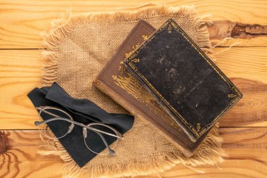 İki eski nadir kitap, gözlüklü ve tahta bir masanın üzerinde jüt peçete, yakın plan, üst manzara..
