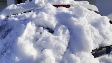 Cleaning car back windscreen from snow with the brush tool, sunny winter day