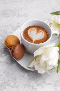Cup of coffee and two macarons on the grey stone background 